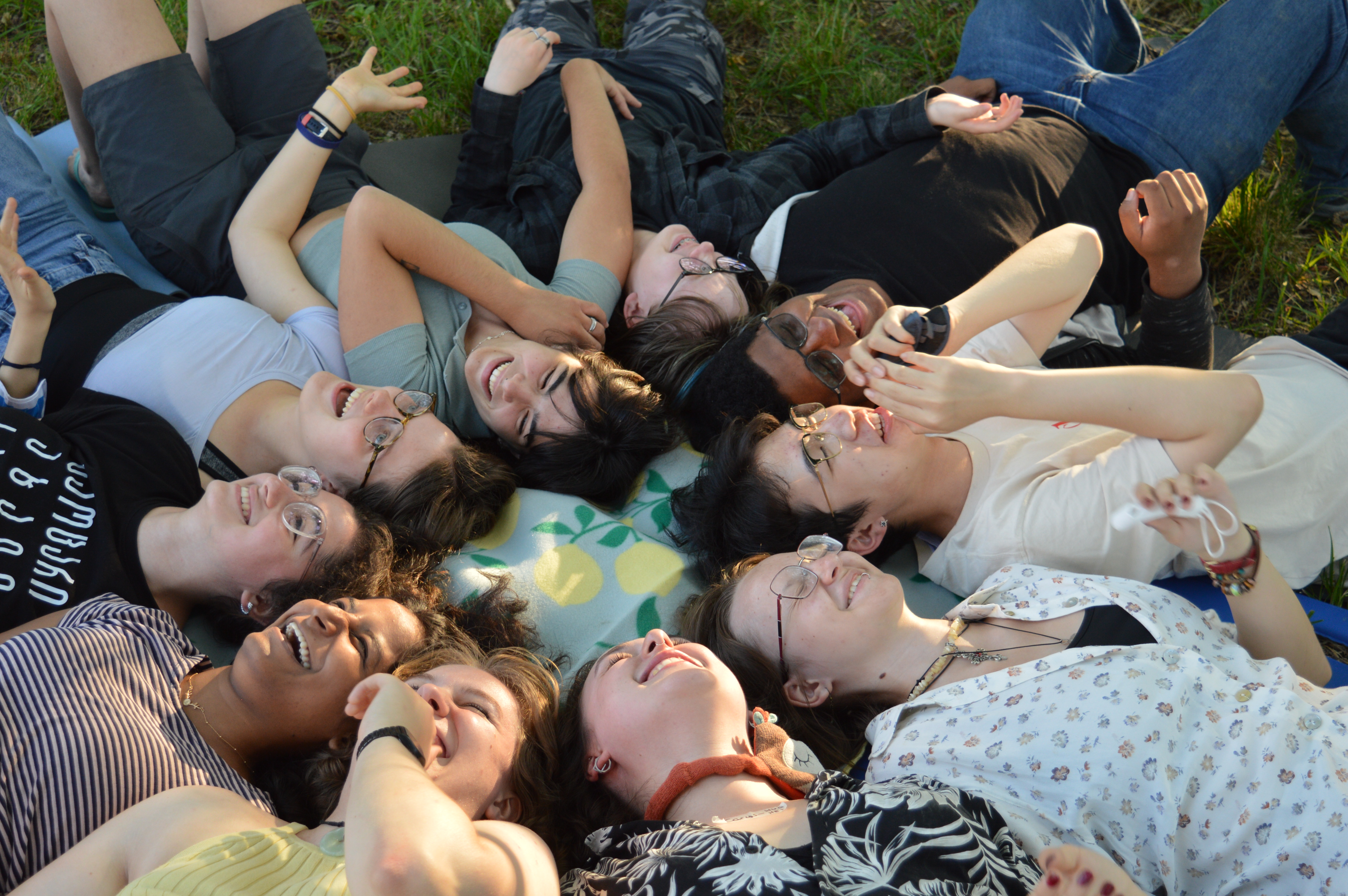 Participants laying back in the grass with their heads touching.