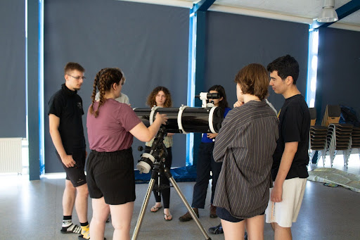 Participants gathered around a telescope indoors.